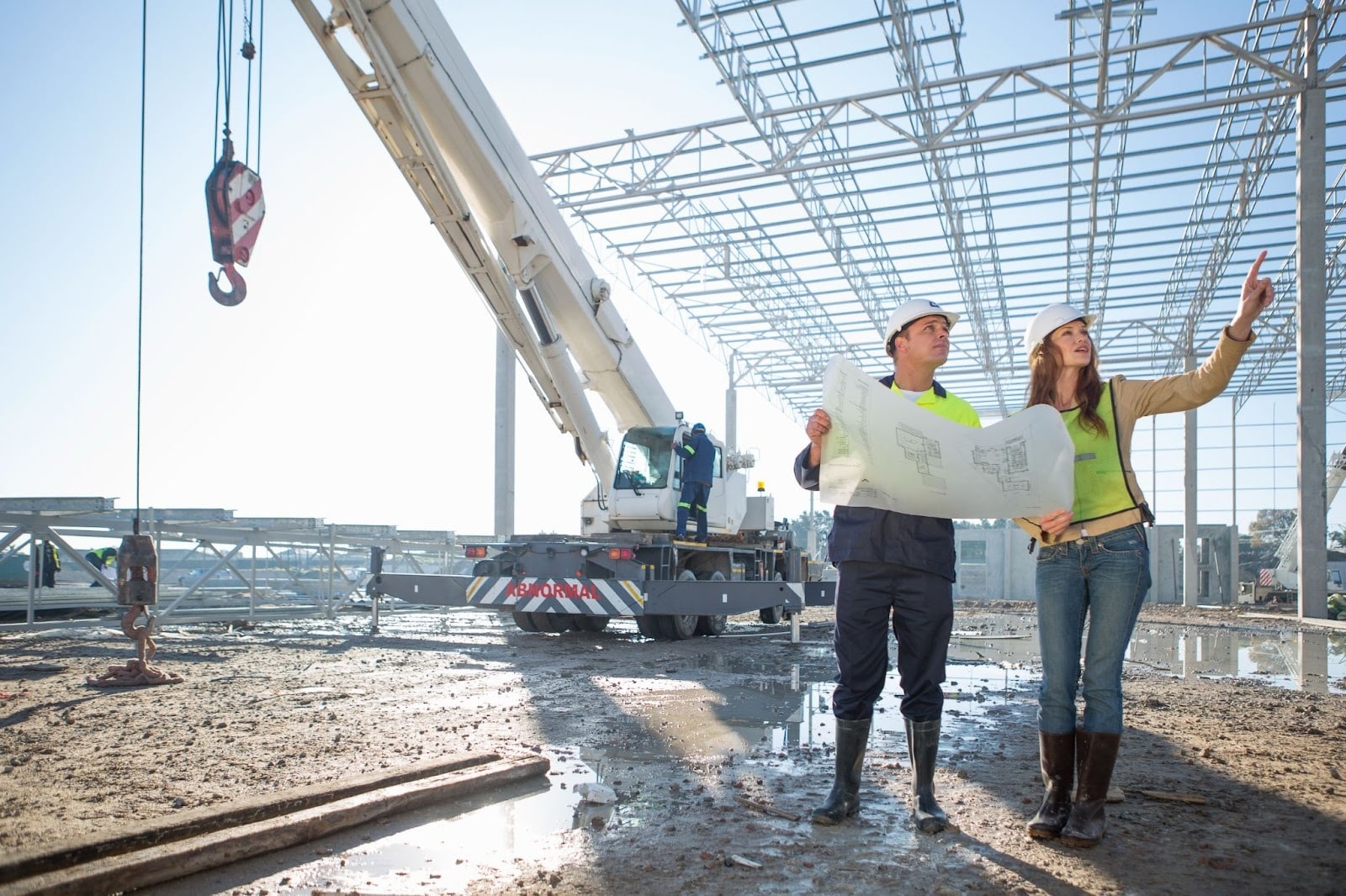 Site manager and architect reviewing detailed blueprints together at an active construction site