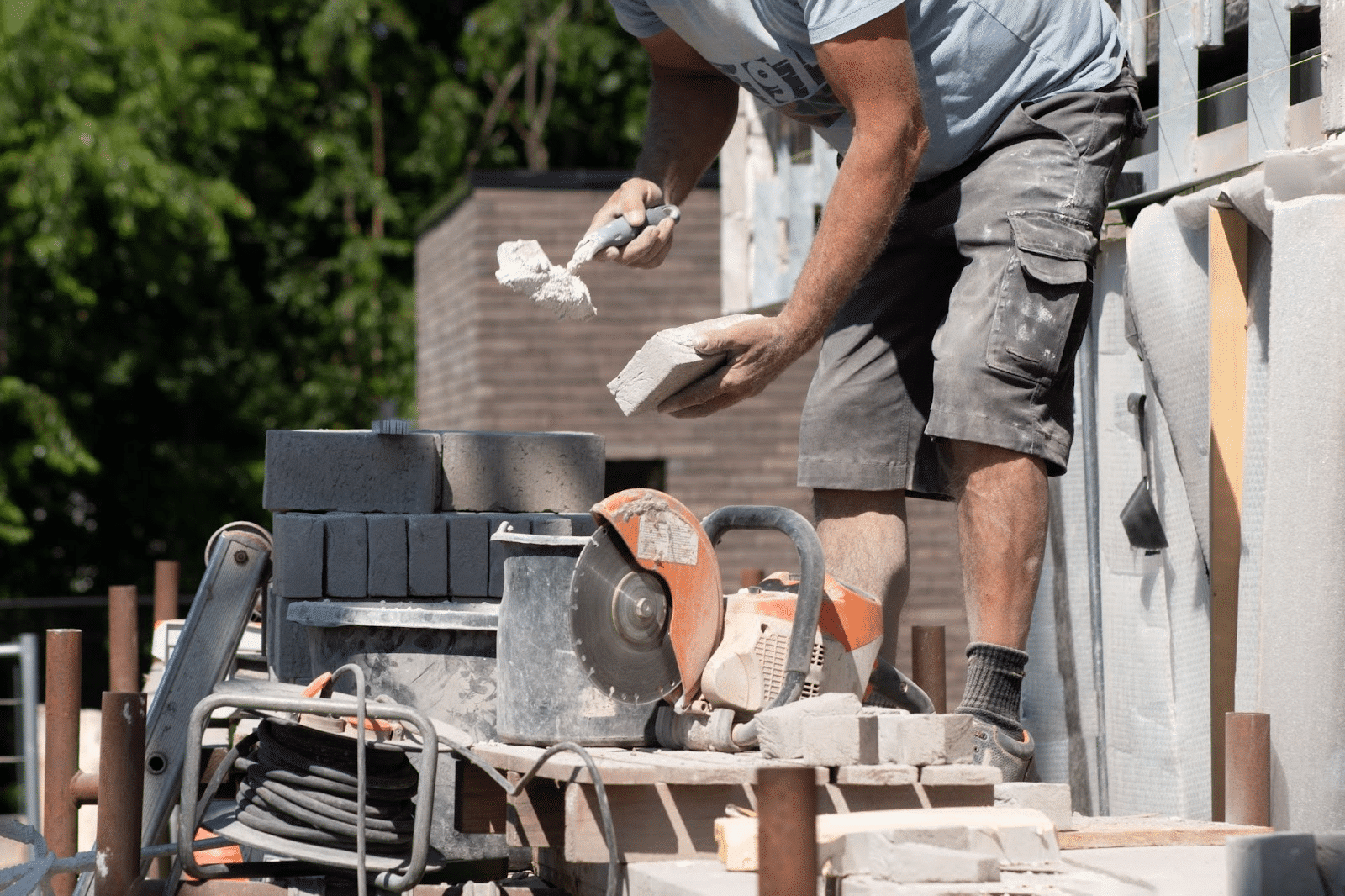 A masonry contractor applies concrete to a stone to build a facade.