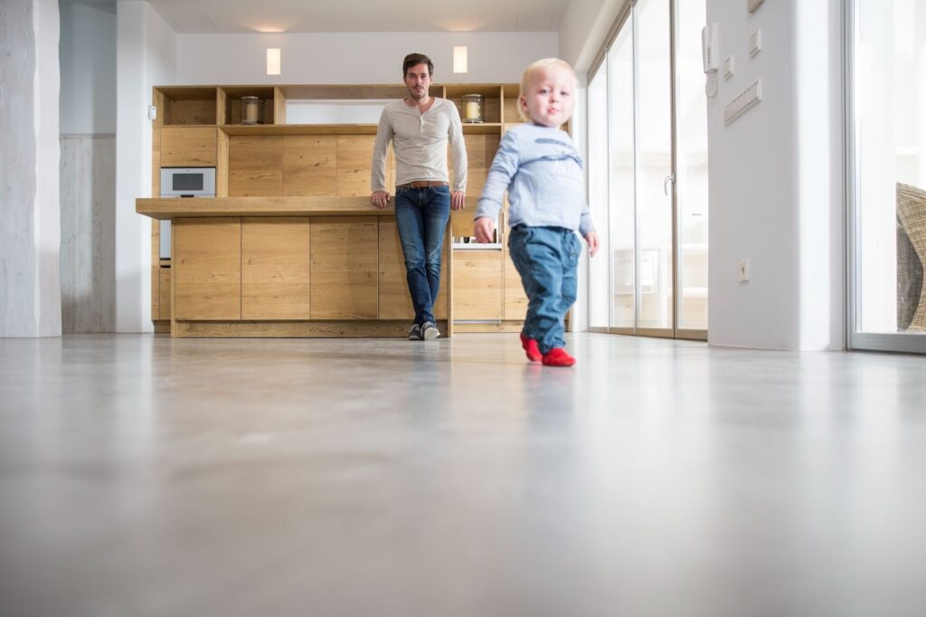 Father watching his young son take first steps on the sleek epoxy dining room floor