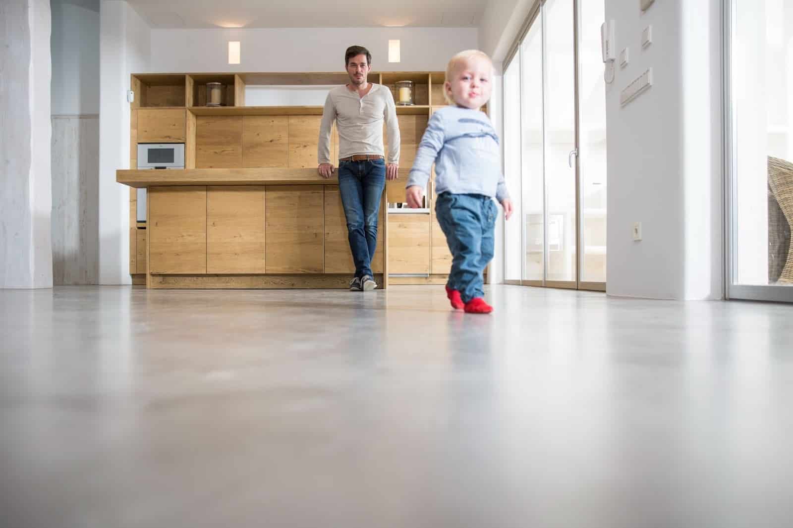 Father watching his young son take first steps on the sleek epoxy dining room floor