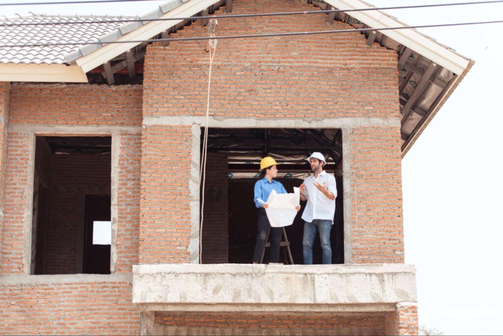 An architect and engineer from a construction company reviews progress at a residential build site.