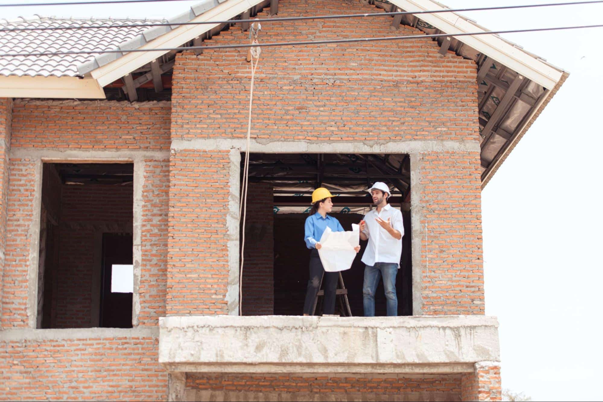An architect and engineer from a construction company reviews progress at a residential build site.